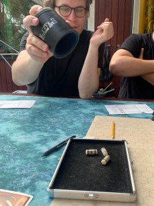 Pelaaja heittämässä noppia noppakupin avulla.